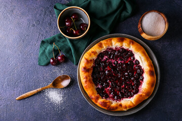 Plate with tasty cherry khachapuri on dark background