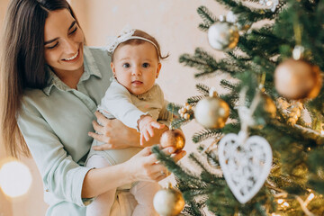 Mother with baby daughter dacorating christmas tree