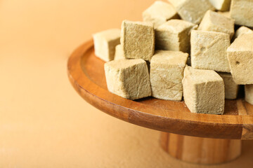 Stand with tasty hojicha marshmallows on color background, closeup