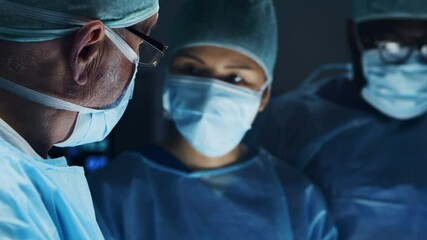 Multiracial team of professional medical surgeons performs the surgical operation in a modern hospital. Doctors are working to save the patient. Medicine, health, cardiology and transplantation. - Powered by Adobe