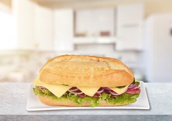 Yummy baguette sandwich with various vegetables and slices of cheese on the desk