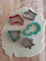 Cutting gingerbread cookies from rolled out dough. Gingerbread cookies. Making gingerbread cookies. Christmas baking background dough, cookie cutters. Viewe from above