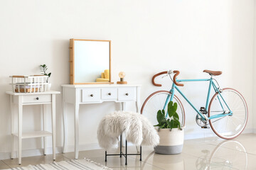 Interior of light room with dressing table and bicycle