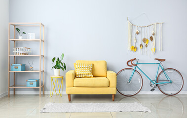 Interior of light living room with yellow armchair and bicycle