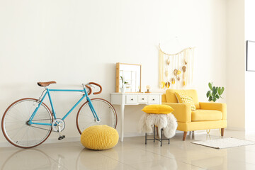 Interior of light room with yellow armchair, dressing table and bicycle