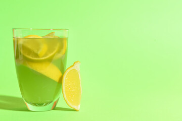 Glass of fresh lemonade on green background