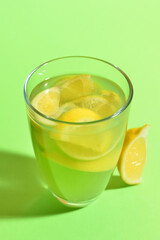 Naklejka na ściany i meble Glass of fresh lemonade on green background