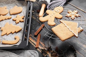 Baking tray and grid with Christmas gingerbread cookies on dark wooden background