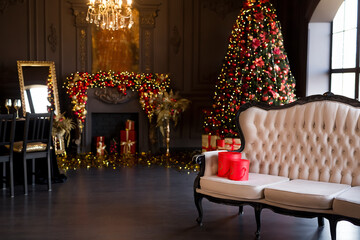 Interior of luxury dark living room with fireplace, comfortable sofa and chandelier decorated with Christmas tree and gifts