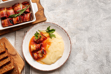 Plate with mashed potatoes, delicious gravy sauce and prunes in bacon on light table