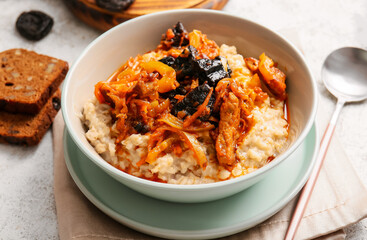 Bowl with delicious oatmeal, gravy with beef and prunes on table, closeup