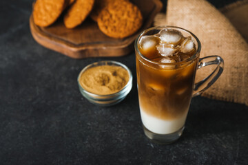 Glass cup of iced hojicha latte on black background