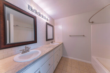 Fototapeta na wymiar Double vanity sink with two framed mirrors and tiles surround
