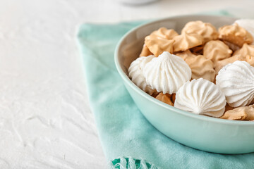 Bowl with tasty meringues on table