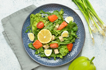 Fresh salad with salmon and vegetables in plate on light background
