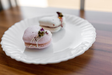 A pink heart-shaped cake lies on a white plate on a light background. Light macaroons on a white canvas. Valentine's Day background