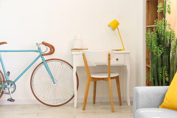 Modern workplace and bicycle near light wall