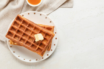 Plate with delicious Belgian waffles and butter on light background