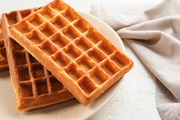 Plate with tasty golden Belgian waffles on light background, closeup