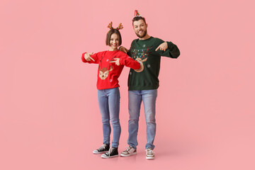 Young couple in stylish Christmas clothes on color background