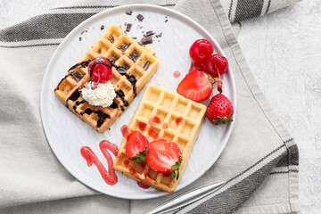 Plate of tasty Belgian Waffles with berries on light background