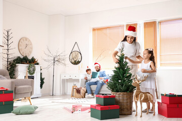 Mother with her little daughter decorating fir tree at home on Christmas eve