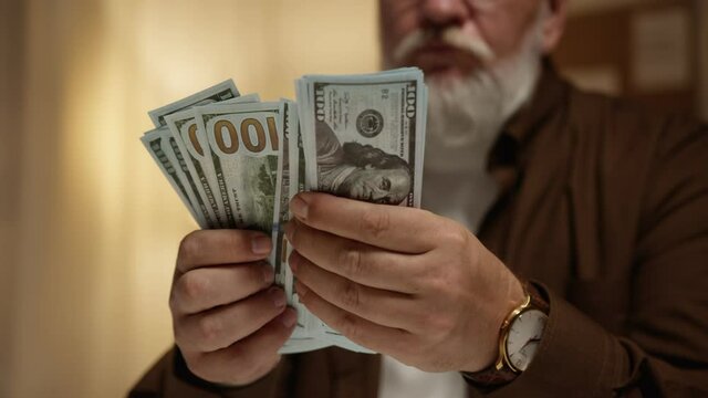 gray-haired man counting dollars close-up