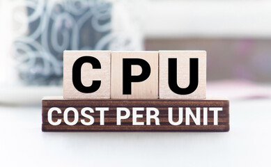 text CPU COST PER UNIT on wooden block, business concept image with soft focus background