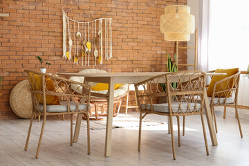 Dining room with wooden table, wicker chairs, armchair and brick wall