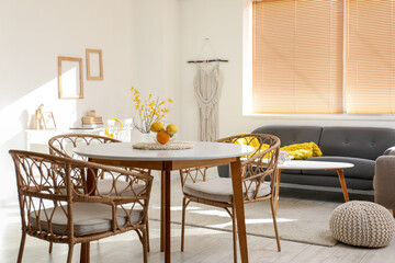 Dining table with oranges and wicker chairs in light room