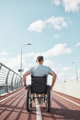 Vertical back view portrait of man in wheelchair in accessible city environment outdoors, copy space