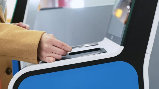 White woman hand applying paper ticket to screen of automatic gate at airport. Printing boarding pass on contactless check-in desk before flight. QR code scanner using at transport terminal entrance 