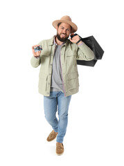 Handsome man with Black Friday shopping bags and gift card on white background