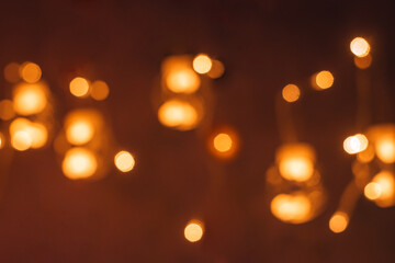 Obraz premium Blurred creative garland of glass balls with burning bulbs inside on a dark background.Festive Christmas and New Year background.Soft focus.