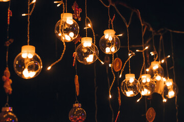 A beautiful creative garland of glass balls with burning bulbs inside on a dark background.Festive...