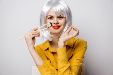 Naklejka premium pretty woman in white wig and sushi with Japanese chopsticks