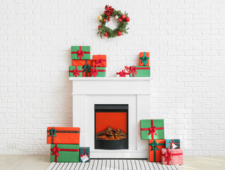 Modern fireplace with Christmas gift boxes near white brick wall