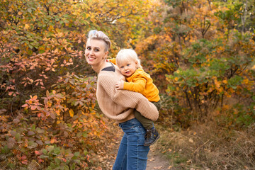 Fototapeta premium happy son with mother in autumn park background with golden trees