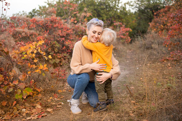 Thanksgiving holiday season. Boy with mother outdoor, autumn background