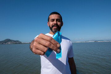 Prostate cancer awareness, man holding light blue ribbon to support people living and disease. World Cancer Day and Men's Health Concept