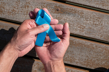 Prostate cancer awareness, man's hand holding a light blue ribbon to support people living and...