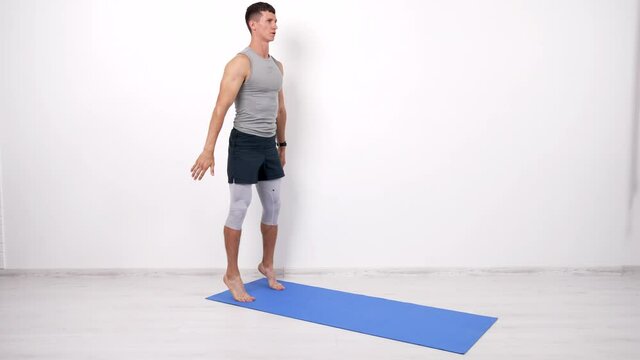 athlet muscular guy doing squats exercise on fitness mat white background, keep fit