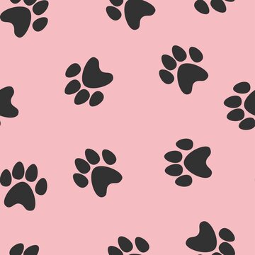 black footprints of a cat on a pink background. seamless abstraction of animal footprints for clothing or print