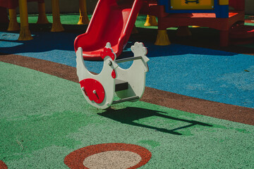 Chicken shape spring rider or rocker on sunny summer day on playground background.
