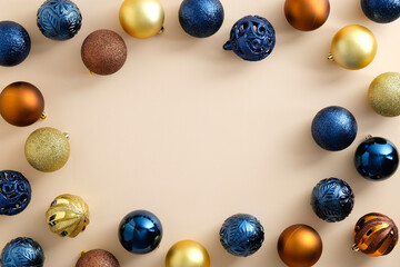 Christmas baubles decoration on pastel beige background with copy space. Blue, golden, and bronze color balls. Merry Christmas and Happy New Year greeting card. Minimal style. Flat lay, top view.