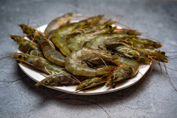 Raw shrimps lie on a white plate.