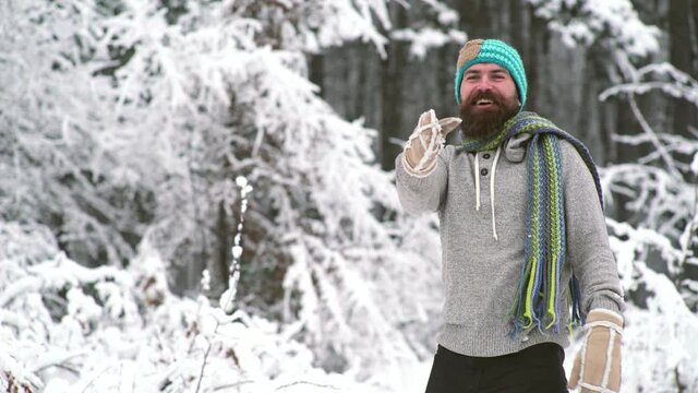 Excited man in hat throwing a snowball. Expression of young man in snowball fight. Winter holiday.
