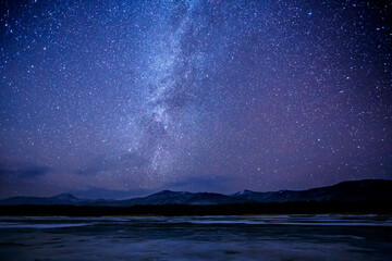 Starry sky over a frozen winter lake. Milky Way. Sikhote-Alin Biosphere Reserve in the Primorsky Territory.