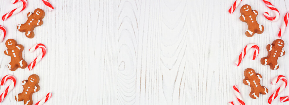 Christmas double border of gingerbread cookies and peppermint candy canes. Top down view on a rustic white wood background with copy space. - Powered by Adobe