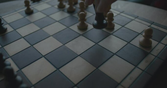Female hand plays a game of chess queen go to king blue hour close up